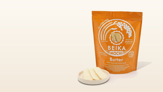 Beika Mochi Butter bag marked 100% Hokkaido Buttermilk beside a white ceramic dish of pale oval rice crackers, the butter senbei this guide examines