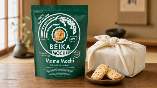 Beika Mochi Mame Mochi pouch standing beside a furoshiki-wrapped gift, an omiyage-style Japanese present